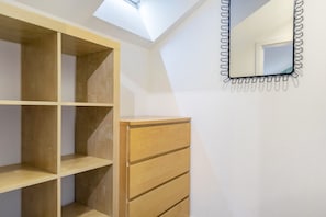 Ein Zimmer mit Oberlichter, Holzregalen, einem Spiegel und einer Holzkommode.
