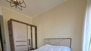 Ein Schlafzimmer mit Bett, Kleiderschrank, Spiegel und einer Kristallleuchtre.