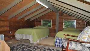 A small, cozy attic bedroom with two beds, a chair, and a window. - 3-bedroom cabin in charming Indian Lake (Indian Lake)