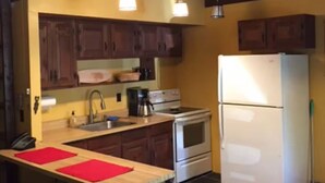 A kitchen with wooden cabinets, a stove, a refrigerator, and hanging pendant lights. - 3-bedroom cabin in charming Indian Lake (Indian Lake)