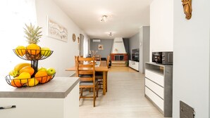 A modern kitchen with a dining area, featuring a built-in microwave, wooden chairs, and a fruit bowl on the counter. - Villa Ariane with pool (Policnik)
