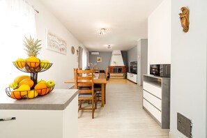 A modern kitchen with a dining area, featuring a built-in microwave, wooden chairs, and a fruit bowl on the counter. - Villa Ariane with pool (Policnik)