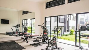 A gym with stationary bikes, treadmills, and a mirrored wall. - Great apartment near the Airport with Air Condit. (Alajuela)