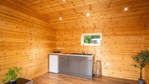 A compact kitchen with wooden walls, a window, and a small sink. - The Cabin  @The Outside Inn (Mountfield)