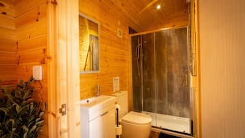 Ein Badezimmer einer Holzhütte mit Toilette, Waschbecken und Dusche.