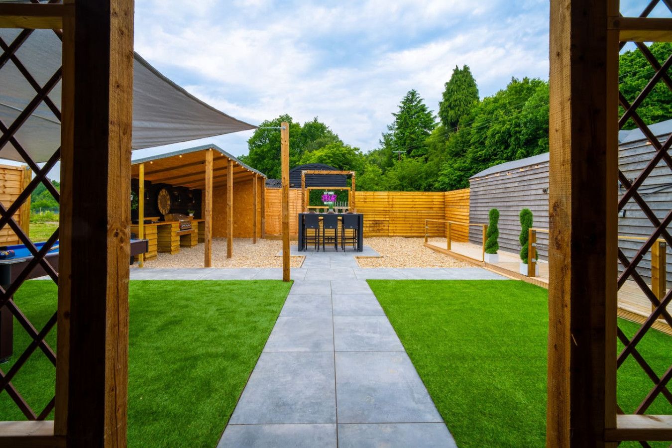 A backyard with a barbecue area, a pool, and a wooden fence.