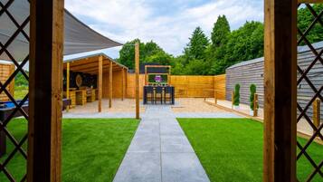 A backyard with a barbecue area, a pool, and a wooden fence.