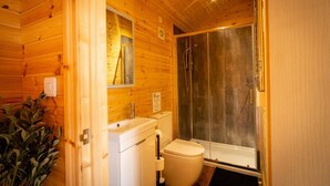 A wooden cabin bathroom with a toilet, sink, and shower. - The Cabin  @The Outside Inn (Mountfield)