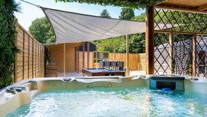 A hot tub with a wooden deck and a table with chairs in the background. - The Cabin  @The Outside Inn (Mountfield)