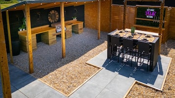 Eine Außenpatio mit einer Holzpergola, einem Grillbereich und einer Sitzgruppe.