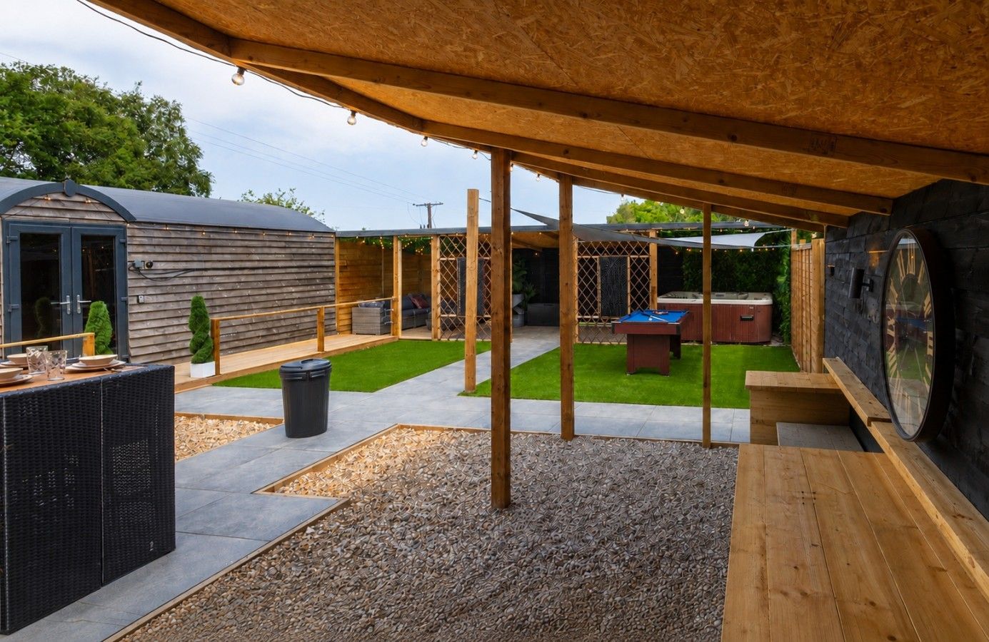 An outdoor patio area with a pool table, seating, and a wooden deck.