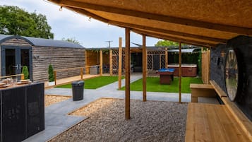 An outdoor patio area with a pool table, seating, and a wooden deck.
