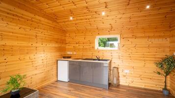 Eine kleine Küche mit Holzwänden, einem Fenster und einem Waschbecken.