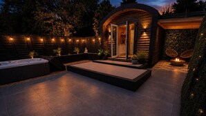 Un patio moderno al aire libre con un jacuzzi, una chimenea y una terraza de madera.