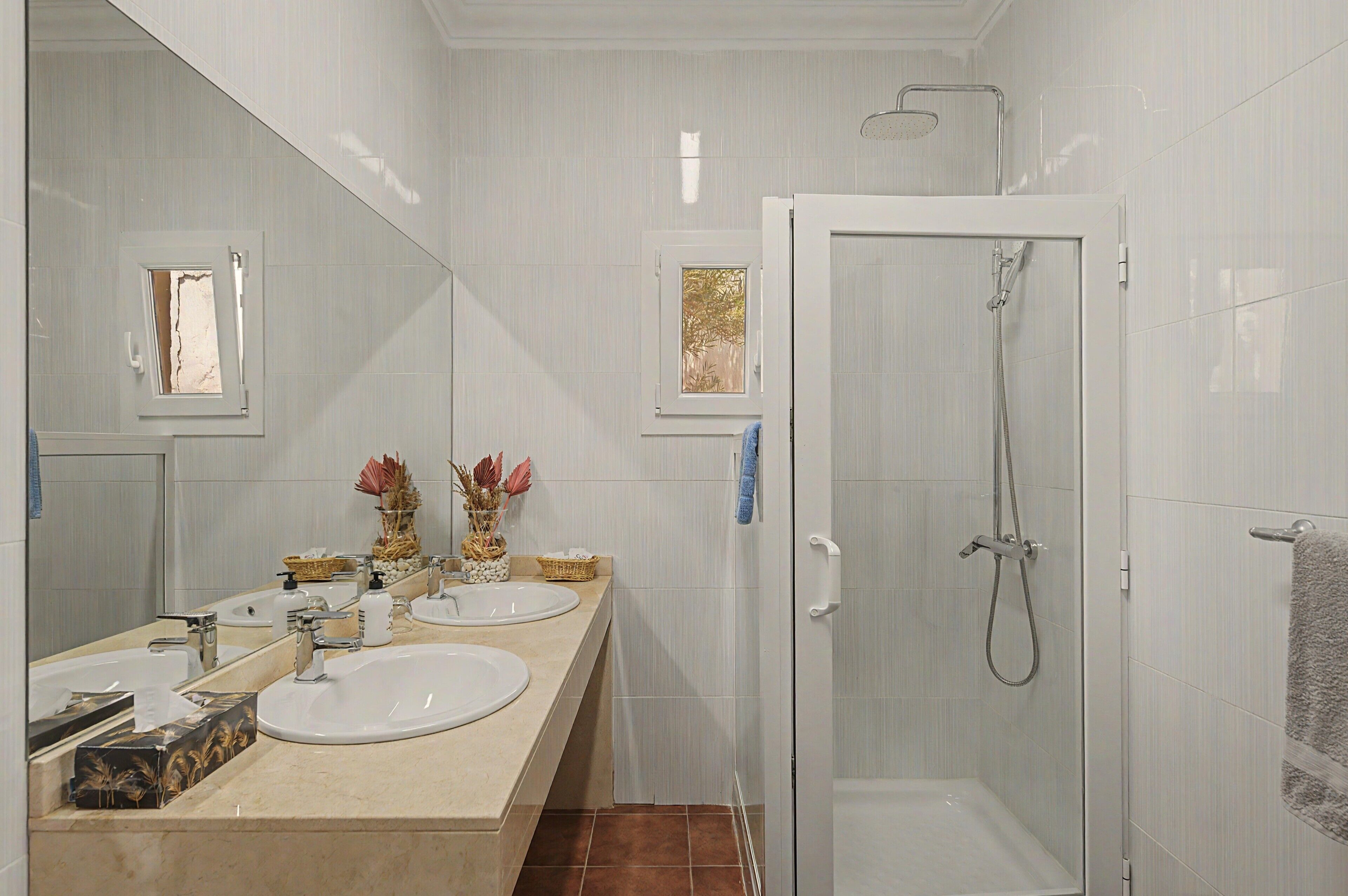 Une salle de bain avec deux lavabos, une douche et un miroir.