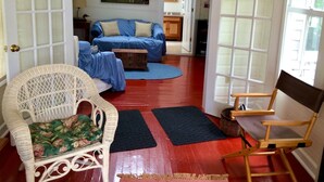 A living room with a wicker chair, a blue sofa, and a wooden chair. - Hearthstone Cottage , Private cottage on Waters Edge! (Blue Hill)