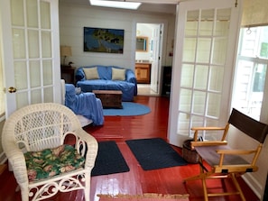 A living room with a wicker chair, a blue sofa, and a wooden chair.