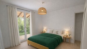 A bedroom with a bed, bedside lamps, a window with curtains, and a view of greenery outside. - Les cabanes (Noaillan)