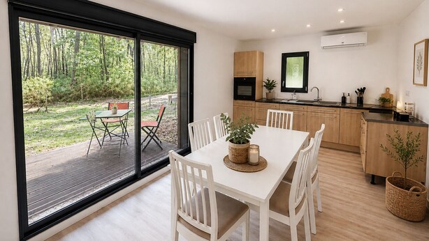 A modern kitchen with wooden cabinets, a built-in oven, and a window overlooking a garden. - Les cabanes (Noaillan)