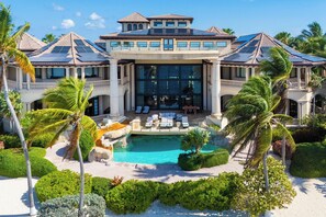 Un gran resort con piscina, palmeras y un área exterior cubierta.