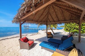 Una cabaña en la playa con muebles de mimbre y vista al océano.