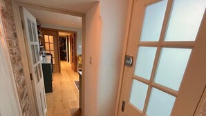 Um corredor com porta, tapete e vista para um quarto com cozinha e sala de jantar.