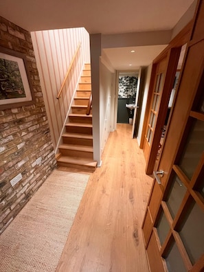 Eine Treppe führt zu einer zweiten Etage, einem Korridor mit Holzdielen und einer Tür mit Fensterteil.