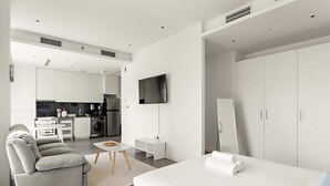 Une chambre d’hôtel moderne équipée d’un lit, d’un canapé, d’une télévision et d’une kitchenette.