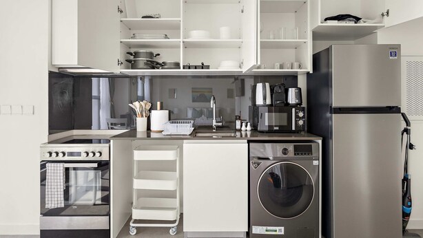 Une cuisine compacte équipée d’une cuisinière, d’un four à micro-ondes, d’un réfrigérateur et d’un lave-linge encastré.