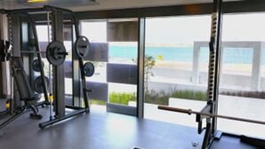 Une salle de sport équipée de matériel de musculation et offrant une vue sur la plage.
