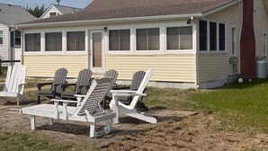 Eenlaags huis met een veranda, schoorsteen en een kleine aangebouwde garage.
