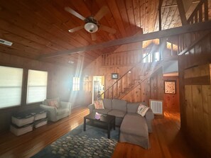 Un interior de madera con sofá, mesa de centro y una escalera.
