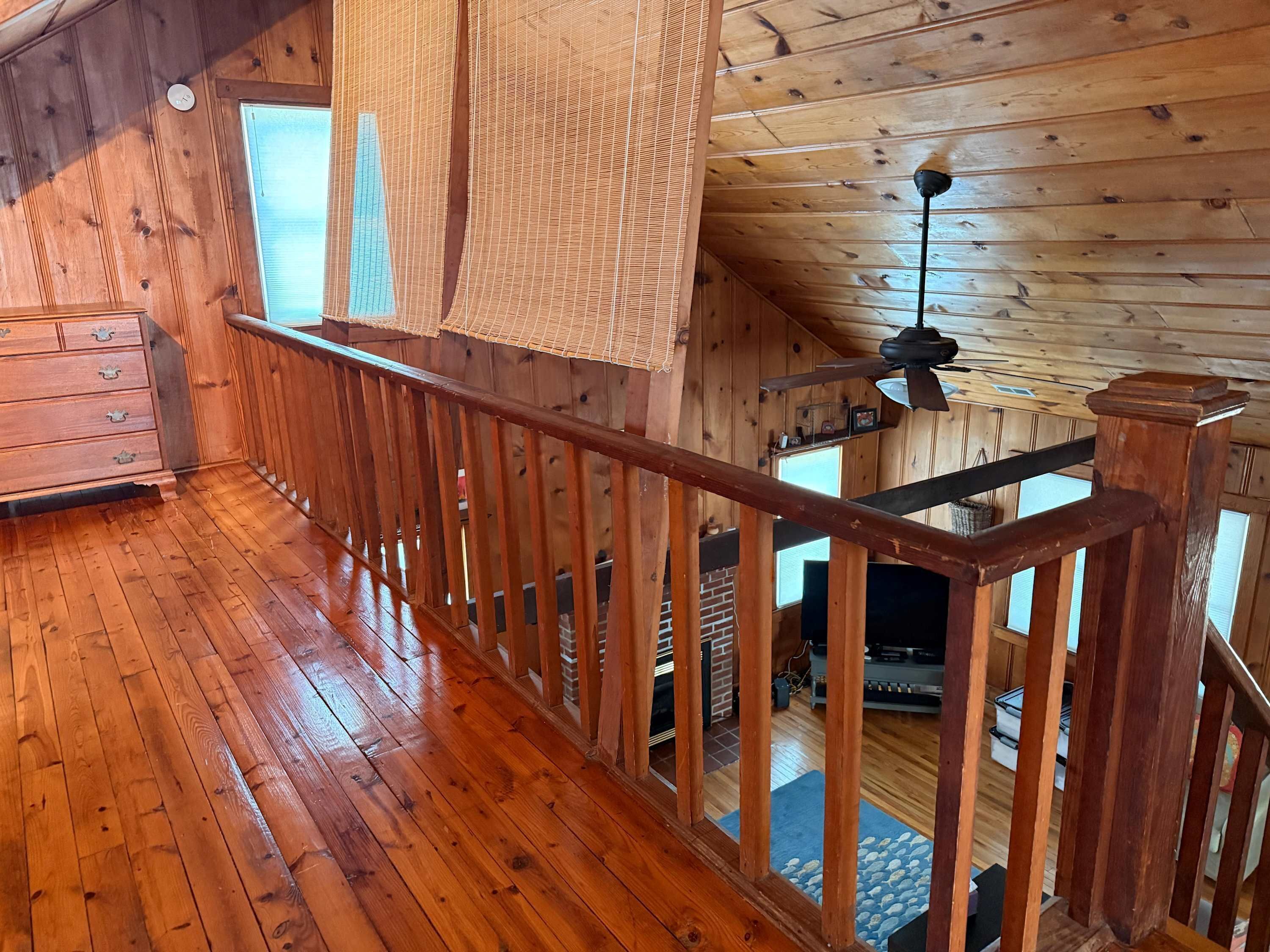 A wooden interior with a balcony, wooden flooring, and a fireplace.