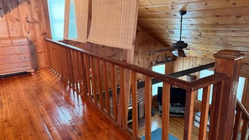 A wooden interior with a balcony, wooden flooring, and a fireplace.