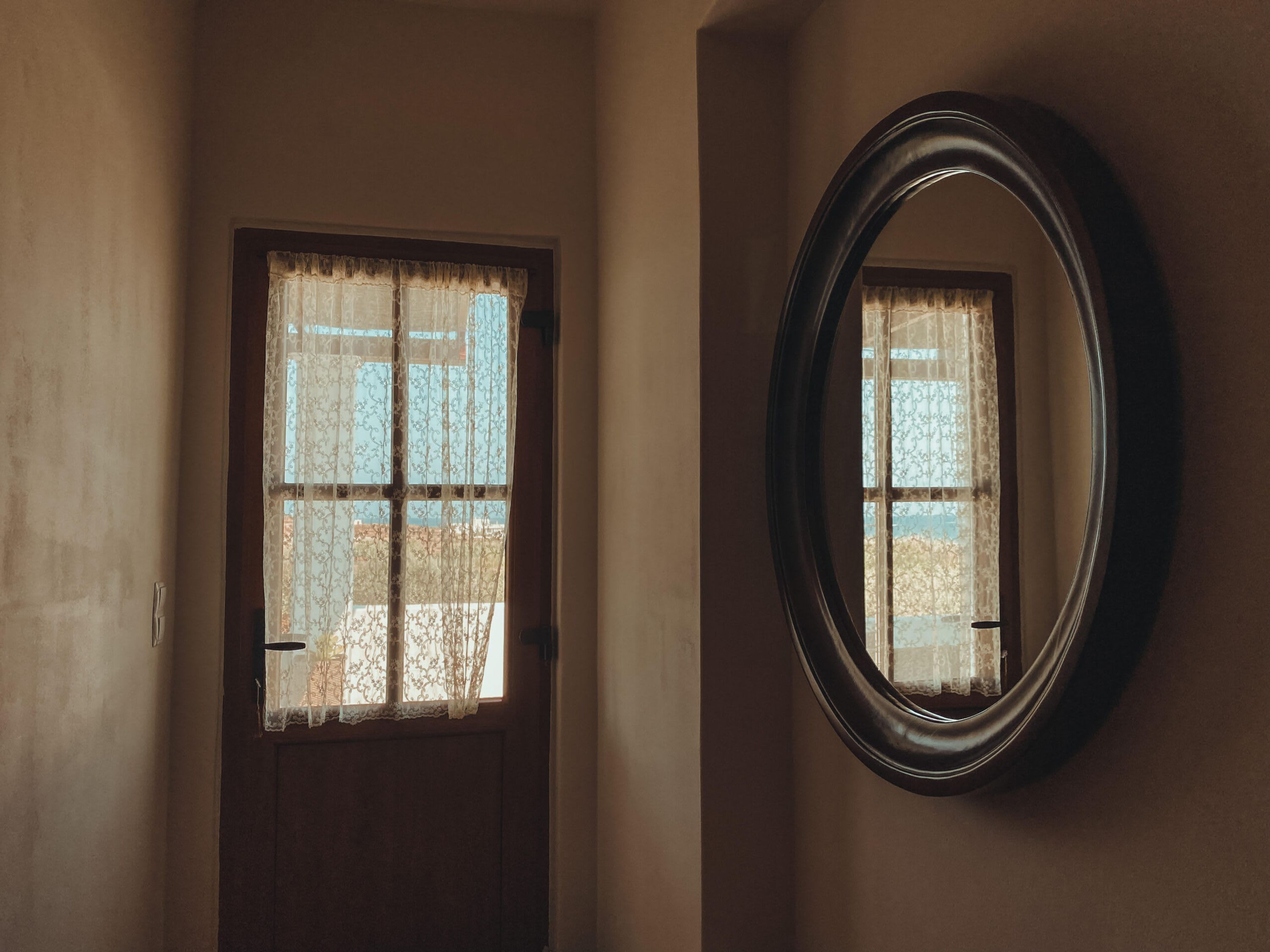 A room with a door and a wall-mounted mirror.