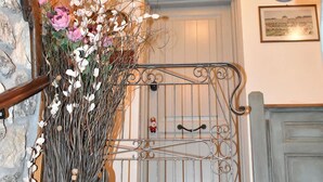 Una escalera con barandilla metálica, un florero con flores y un pasamanos de madera.