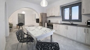 A modern kitchen with a marble countertop, stainless steel appliances, and a large window. - Villa Therme Athen-sea View Jacuzzi Santorini Stay (Santorini)