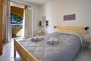 A bedroom with a bed, a wooden headboard, a small stool, a mirror, and a wall-mounted shelf with two lamps. - Seafront Cozy Villa - Corfu Homely Getaway (Corfu)