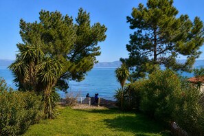 A coastal view with a grassy area, trees, and a fence. - Seafront Cozy Villa - Corfu Homely Getaway (Corfu)
