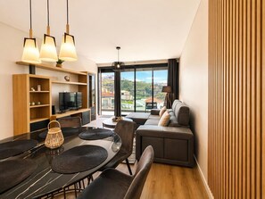 Ein modernes Wohnzimmer mit Essbereich, einer Couch und einem Fernseher.