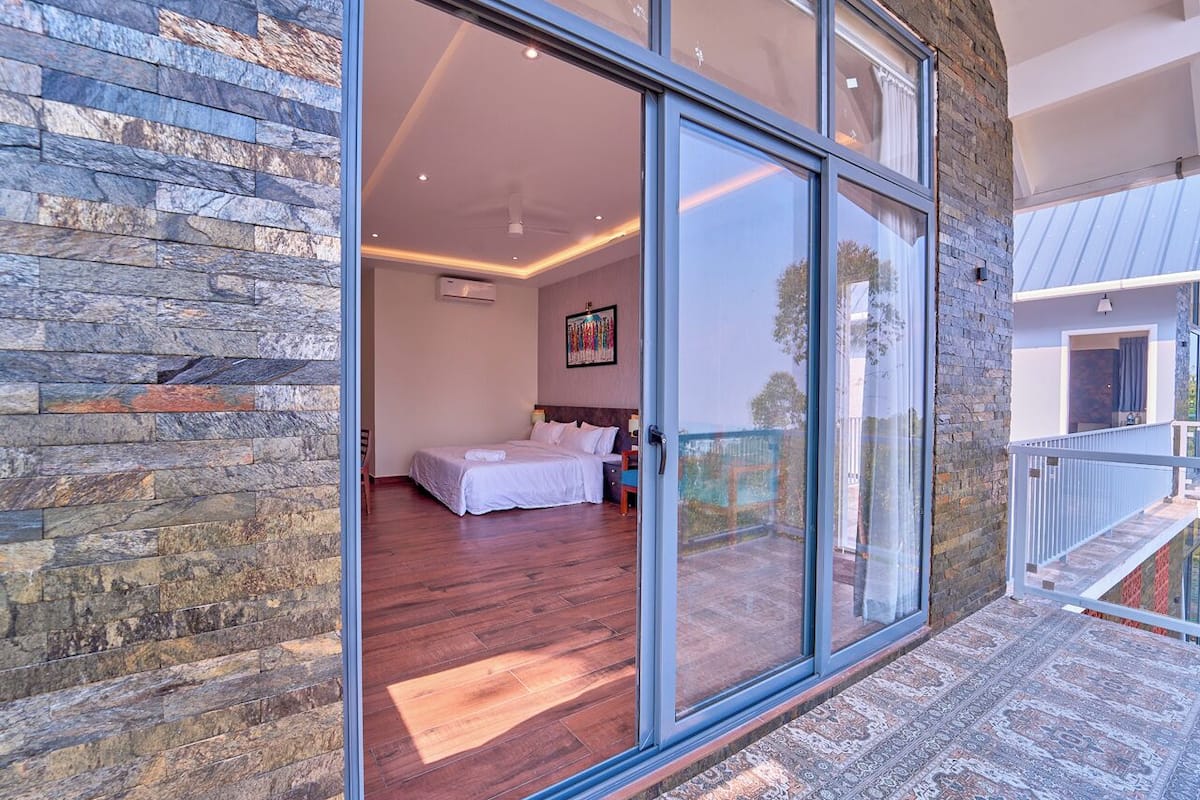 A bedroom with a large sliding glass door, a bed, and a view of the outside.