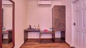 Una habitación con piso de madera, un escritorio con espejo, un dispensador de agua y aire acondicionado instalado en la pared.