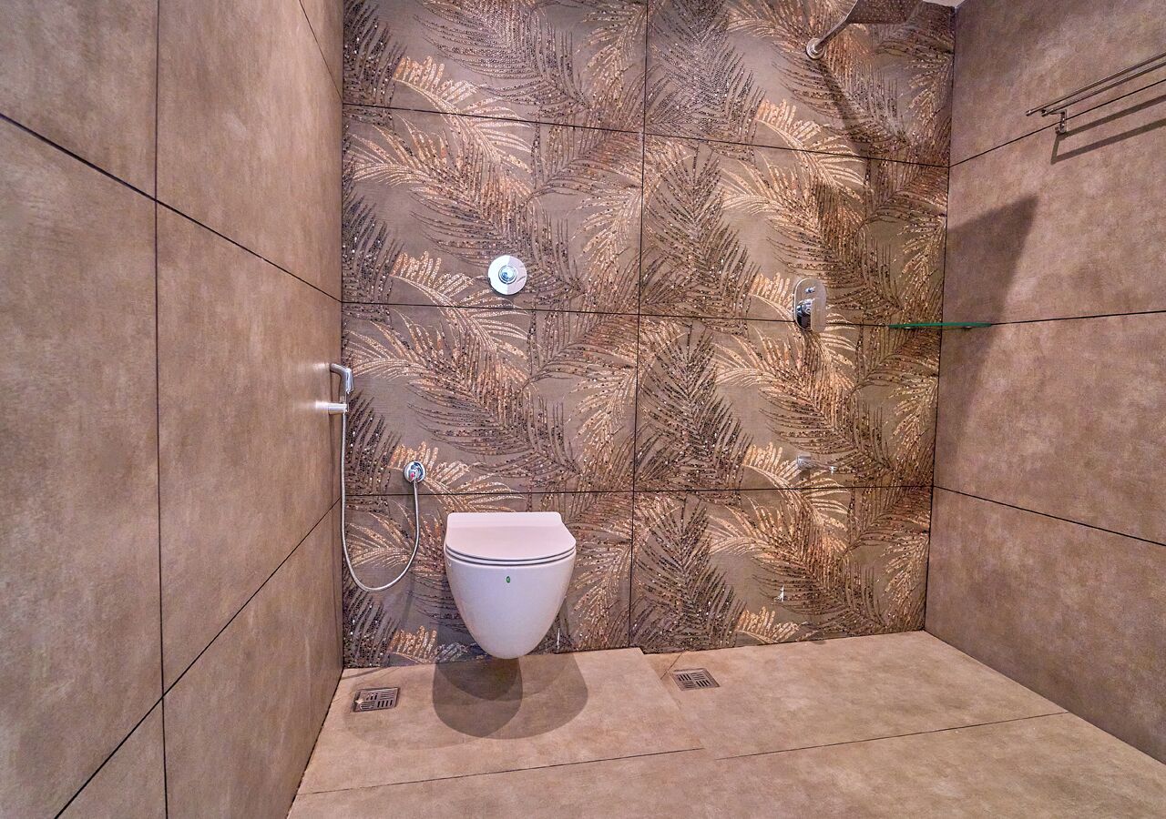 Une salle de bain comprenant des toilettes, un espace douche et un mur décoré d’un motif.