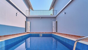 Una piscina en la azotea con vistas despejadas al cielo, un balcón y una puerta.