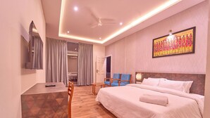 Habitación de hotel con cama, escritorio, silla, televisor y un cuadro en la pared.
