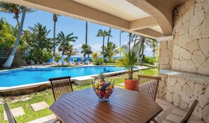 Ein Poolbereich mit Tisch, Stühlen und einer Obstschale.