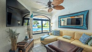 Un salon comprenant un canapé, une table basse, une cheminée, un ventilateur de plafond et une vue sur une piscine.