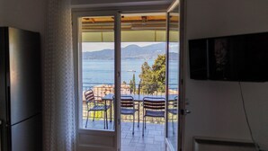 A room with a sliding glass door leading to a balcony with a view of the sea and mountains. - Jordan House (Torri del Benaco)