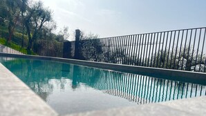 A swimming pool with a metal fence, surrounded by trees and a clear sky. - Jordan House (Torri del Benaco)
