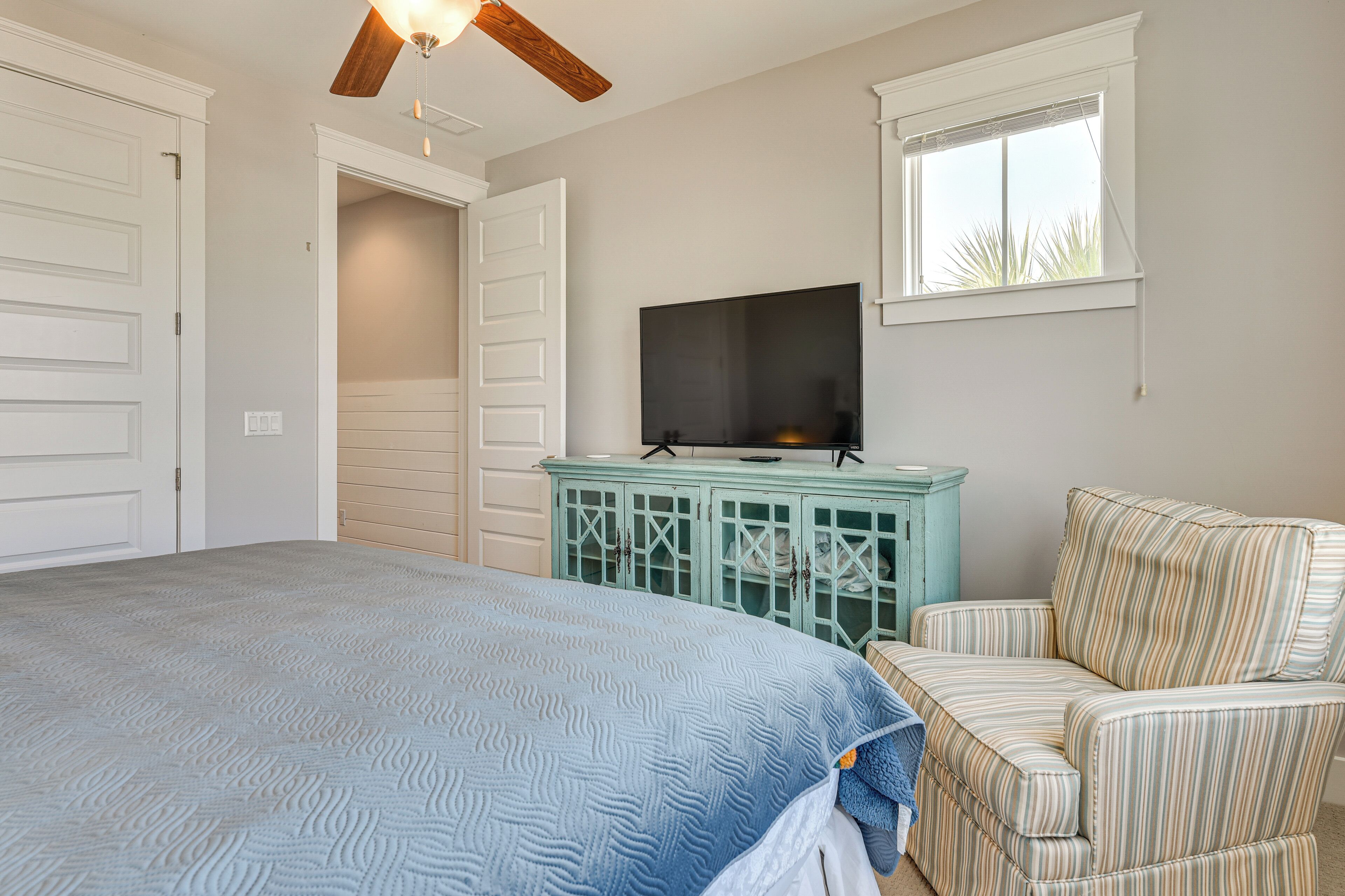 A bedroom with a bed, a television, a window, and a door.